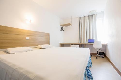 a bedroom with a large white bed and a desk at Rede Andrade Express in Salvador