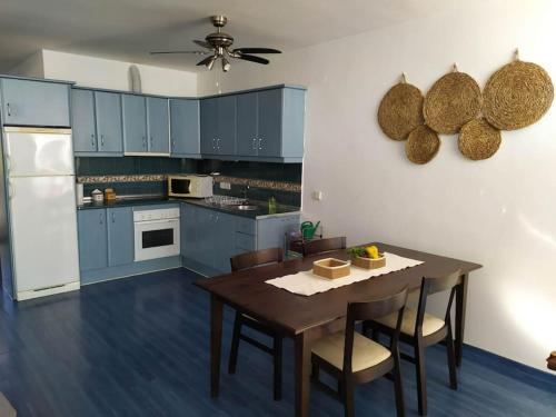 cocina con armarios azules, mesa y sillas en Beachfront apartment en Estepona