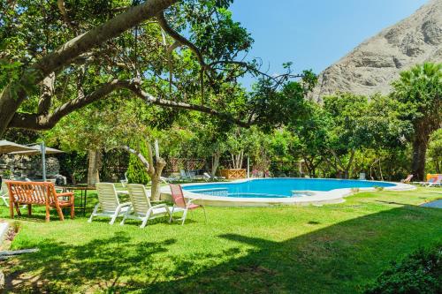 a yard with chairs and a swimming pool at Hotel Rumi Wasi in Lunahuaná
