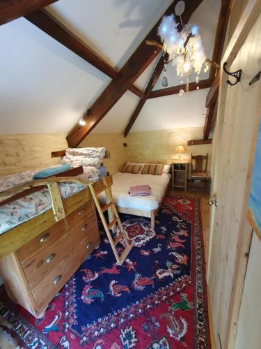 1 dormitorio con cama y alfombra en el ático en Driftwood Cottage, en Yelverton