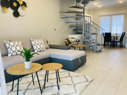 a living room with a couch and a spiral staircase at Tóparti Apartmanház in Balatonszárszó