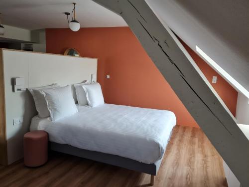 a bedroom with a white bed with an orange wall at Apparthotel Privilodges Le Royal in Annecy