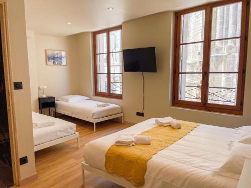 une chambre d'hôtel avec deux lits et une télévision dans l'établissement La Collégiale, à Saint-Aignan