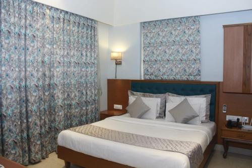MUZA HOTELS FISCO في مومباي: غرفة فندقية بسرير وستارة