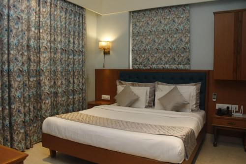 MUZA HOTELS FISCO في مومباي: غرفة نوم بسرير كبير ونافذة كبيرة