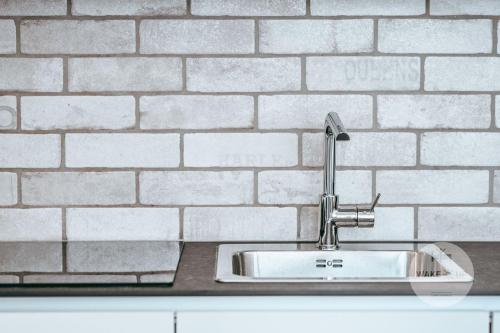 a sink in front of a white brick wall at WakeUp Esch-City in Esch-sur-Alzette