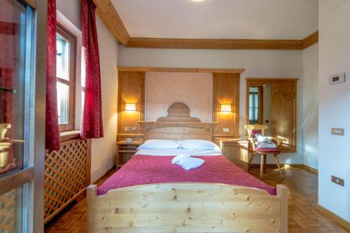 1 dormitorio con cama de madera y manta roja en Park Hotel Sport, en Andalo