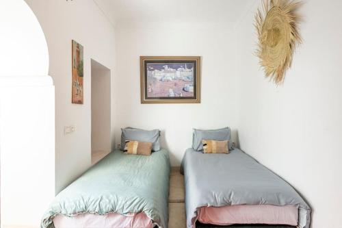 two twin beds in a room with white walls at RIAD ALGHANI in Marrakech