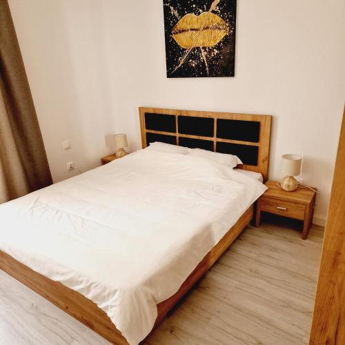 um quarto com uma cama grande e lençóis brancos em Comfort cosmopolis em Ştefăneştii de Jos