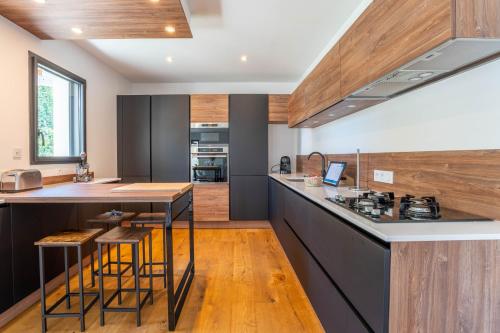 une cuisine avec un comptoir et un îlot de cuisine avec des tabourets dans l'établissement Banana Beach - Magnifique Villa contemporaine vue mer plage à 20 m avec paddles, à Sarzeau