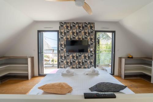 - une chambre avec un lit et une télévision murale dans l'établissement Banana Beach - Magnifique Villa contemporaine vue mer plage à 20 m avec paddles, à Sarzeau
