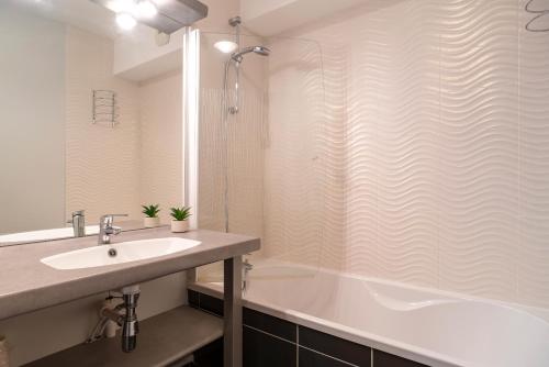 La salle de bains est pourvue d'une baignoire, d'un lavabo et d'une douche. dans l'établissement Les Thermes 521 - Appt proche plage avec piscine partagée, à Concarneau