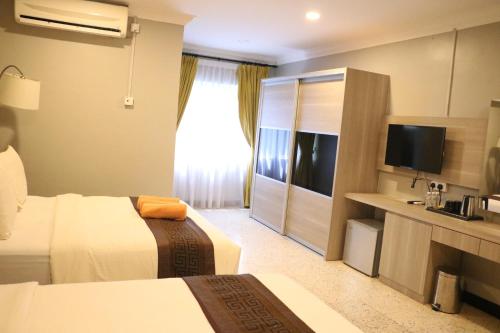 a hotel room with two beds and a flat screen tv at Hotel Felda Residence Tekam , PPP Tun Razak in Kampong Sungai Batu