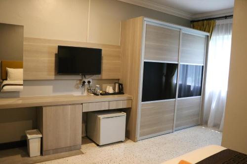 a hotel room with a desk with a tv and a closet at Hotel Felda Residence Tekam , PPP Tun Razak in Kampong Sungai Batu