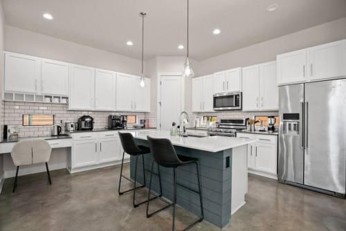 a large kitchen with white cabinets and a refrigerator at Grand Oasis At E Austin With Pool in Austin