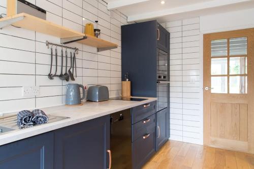uma cozinha com armários azuis e um lavatório em Stac Polly Cottage by Porthleven & Lizard Holidays em Helston