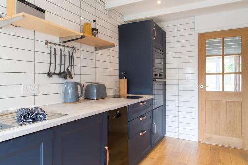 a kitchen with blue cabinets and a sink at Stac Polly Cottage by Porthleven & Lizard Holidays in Helston