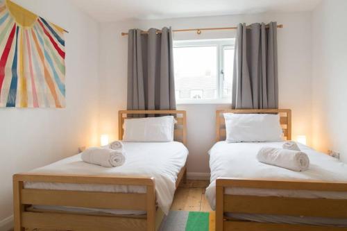 two twin beds in a room with a window at Stac Polly Cottage by Porthleven & Lizard Holidays in Helston