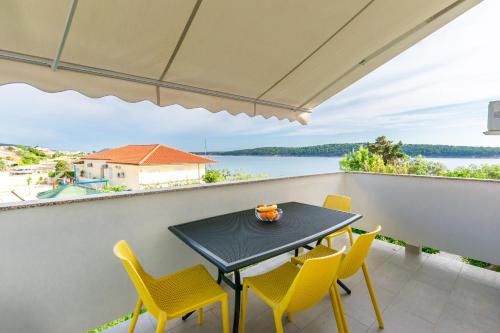 a table and chairs on a balcony with a view of the water at Apartments and Rooms Bianca in Barbat na Rabu