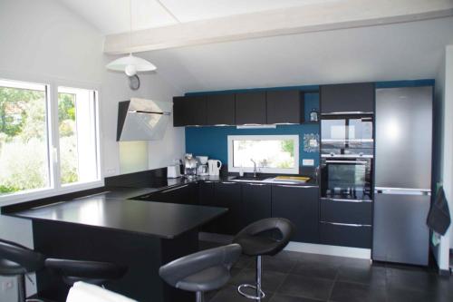 une cuisine avec un comptoir noir et des armoires bleues dans l'établissement 3 pièces dans le ciel, à Gattières