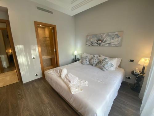 1 dormitorio con 1 cama con sábanas y almohadas blancas en Résidence Le Vizir Center Rez de jardin, en Marrakech