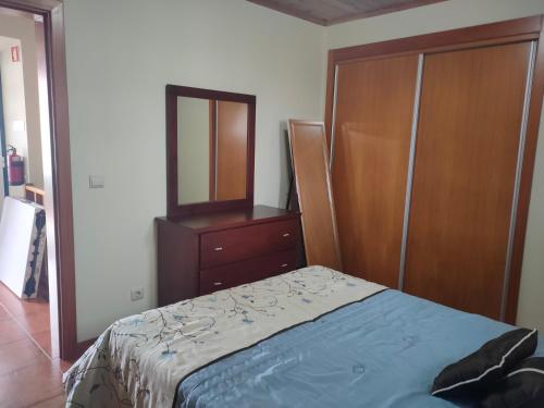 a bedroom with a bed and a dresser and a mirror at Casa dos Avós 2 in São Roque do Pico