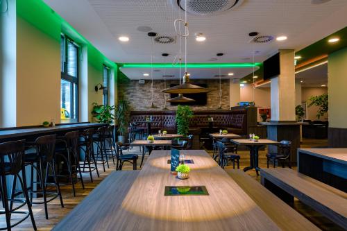 a restaurant with wooden tables and chairs and green lighting at ibis Styles Kiel City in Kiel