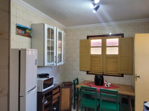 Il comprend une cuisine équipée d'une table, de chaises et d'un réfrigérateur. dans l'établissement Apartamento completo no Centro histórico, à Ouro Preto