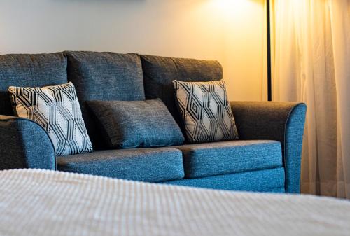 a blue couch with pillows sitting next to a bed at Trade Winds Hotel in Dickenson Bay