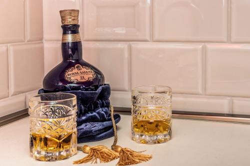 a bottle of whiskey and two glasses on a counter at Apartments Dončić in Kotor