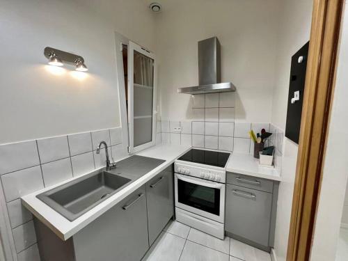 uma cozinha branca com um lavatório e um fogão em Le Multipliant em Montpellier