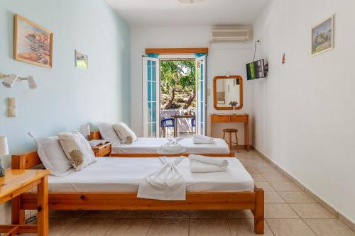 a room with two beds and a table and a mirror at Seaview Mastrozanne Studio 9 Andros in Andros