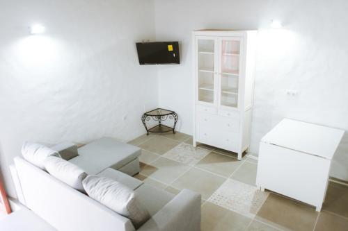a living room with a white couch and a tv at Casita do Castelo in Lourinhã