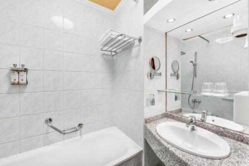 a white bathroom with a sink and a mirror at Danubius Hotel Arena in Budapest