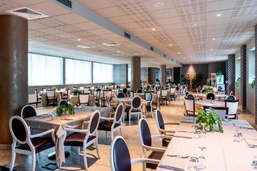 una sala de banquetes con mesas y sillas en una habitación con ventanas grandes en Hotel Parisi, en Nichelino