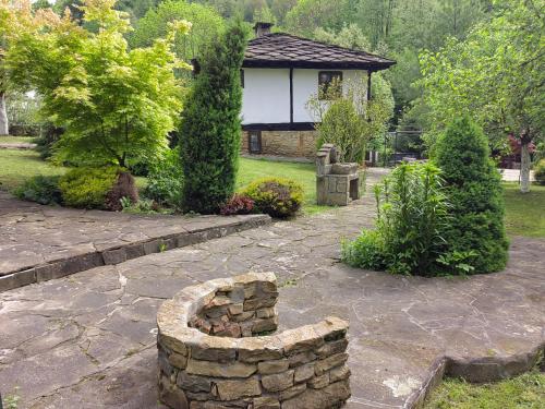 a stone fire pit in front of a house at Къща за гости КИМ in Apriltsi