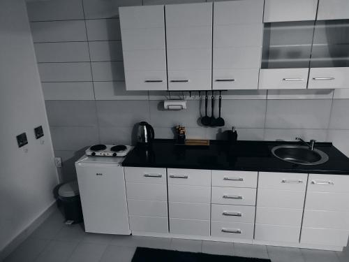 a white kitchen with a sink and white cabinets at Apartman Katy in Sremska Mitrovica