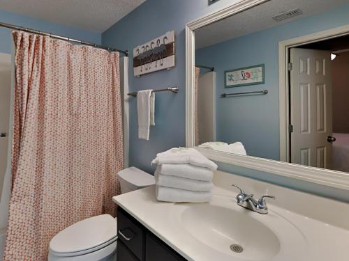 een badkamer met een wastafel, een toilet en een spiegel bij Tidewater orange Beach 209 in Orange Beach