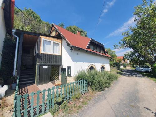 Casa blanca con techo rojo y valla en Kisház a hegyen, en Csopak