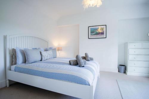 a white bedroom with a bed with blue pillows at Penlan - 3 Bedroom Cottage - Saundersfoot in Saundersfoot