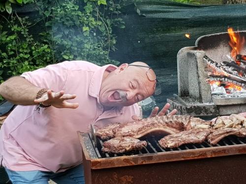 a man is cooking meat on a grill at Camping al Lago in Tarzo