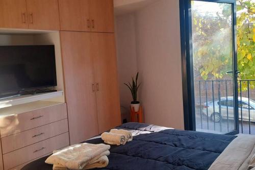 Schlafzimmer mit einem Bett, einem TV und einem Fenster in der Unterkunft Moderno departamento in Godoy Cruz