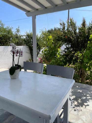 un tavolo bianco con due sedie e un vaso con fiori di Alesta a Aggelika