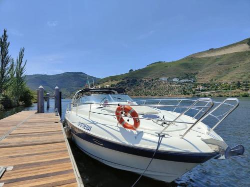 un barco blanco atracado en un muelle en el agua en Douro - Noite a Bordo, en Tabuaço