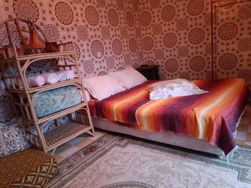 - une chambre avec un lit et une couverture colorée dans l'établissement Appartement dans la médina, à Assilah