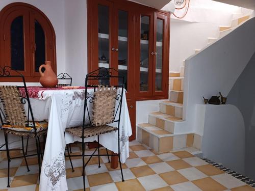 uma sala de jantar com mesa, cadeiras e escadas em Appartement dans la médina em Arzila