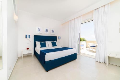 a white and blue bedroom with a bed and a balcony at Residenza Al Pesce D'Oro in Amalfi