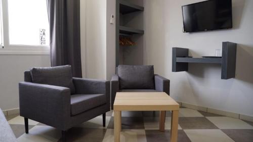 two chairs and a table in a room with a tv at riad casa bahia asilah in Asilah
