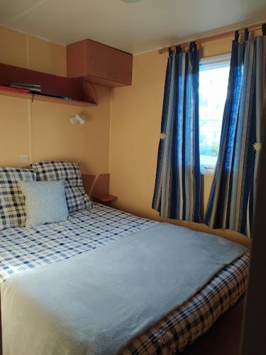 a bedroom with a bed with blue curtains and a window at Le Paradis Bleu camping les pins maritimes in Hyères