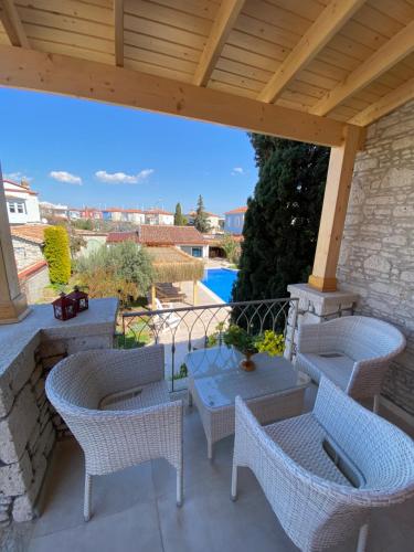 un patio con sillas y mesas de mimbre y pérgola de madera en Alacati Gubiba Evleri en Alacati